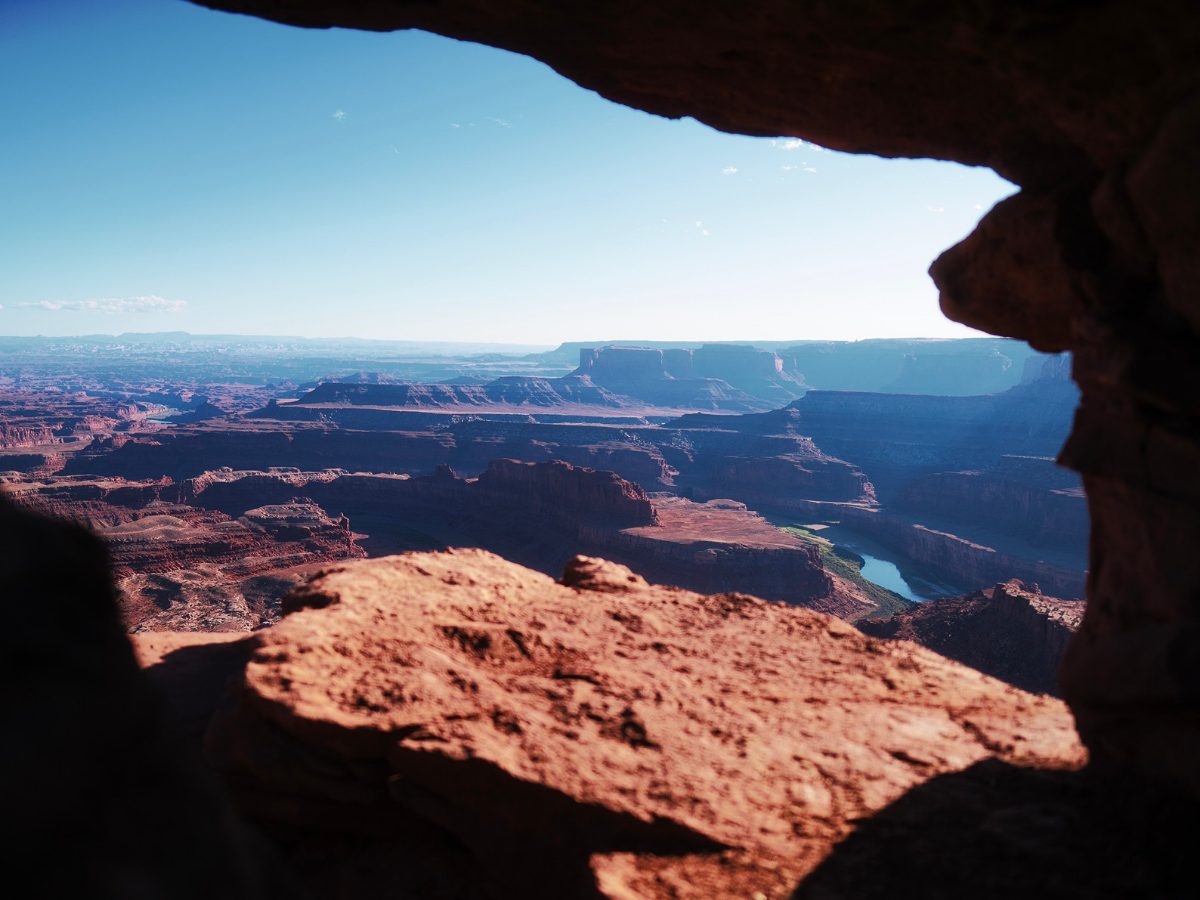Red canyon layers and a winding river seen through a sandstone rock opening, edited with Fujifilm Profiles