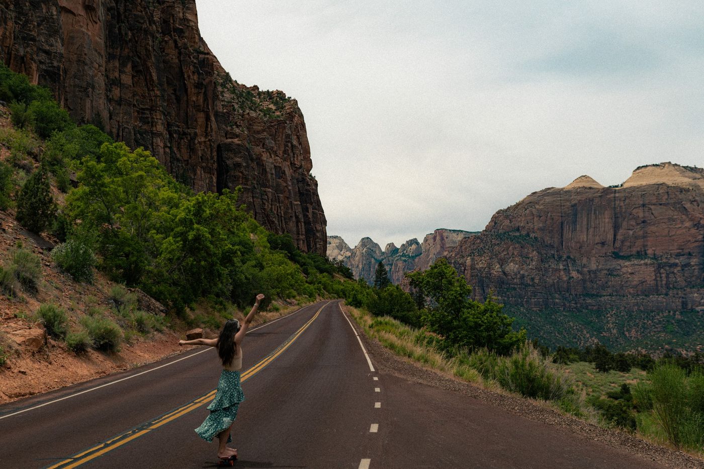 A woman walking a road through red canyon cliffs