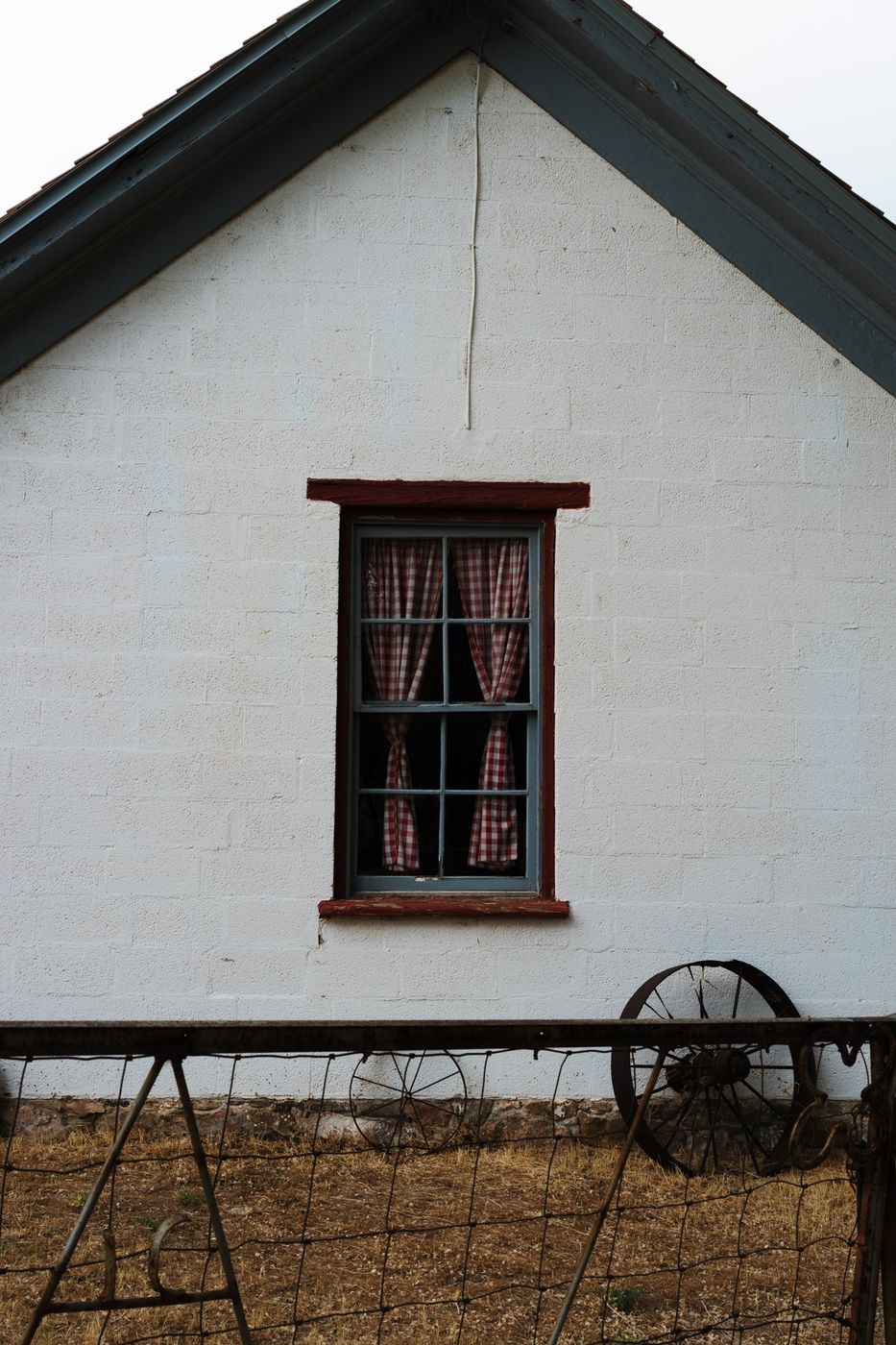 A white farmhouse with a red window frame, with Astia