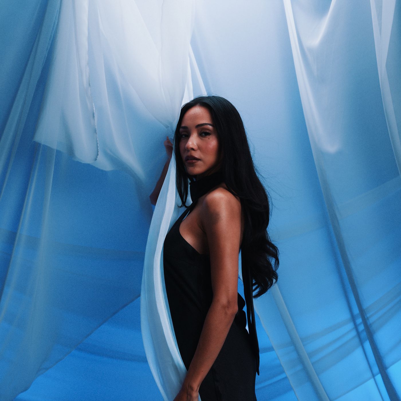 A woman in front of blue curtains, edited with Feria