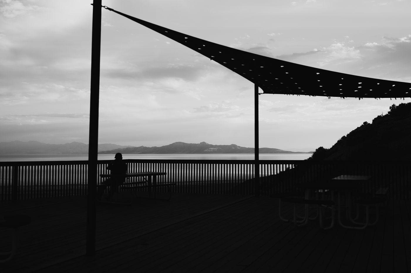 A shade sail over a lake view, high contrast, edited with Ceniza